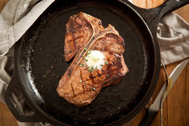T-Bone steak dans la poêle avec une noix de beurre.