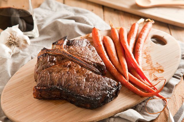 T-Bone steak sur une planche à découper avec des carottes.