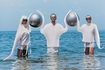 Des personnes en costumes futuristes debout dans l'océan