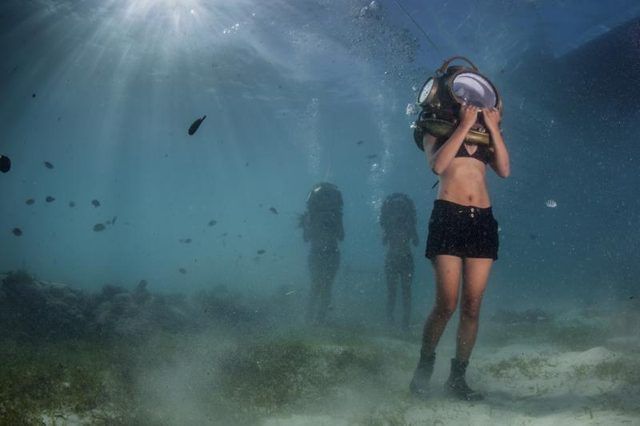 Femme marchant sous l'eau, le port d'un casque de plongée antique