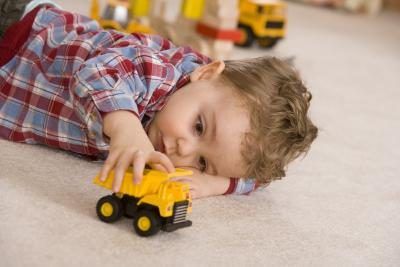 Jeune garçon jouant avec la voiture de jouet jaune.