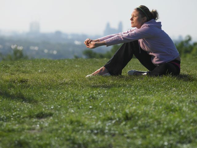Une femme étend dans l'herbe avec les toits de la ville dans la distance.