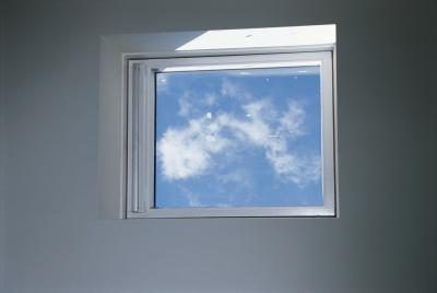 Mur peint en gris avec une fenêtre montrant le ciel bleu.
