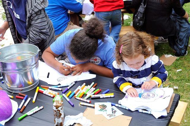 Enfants faire de l'art à une table lors d'un festival.