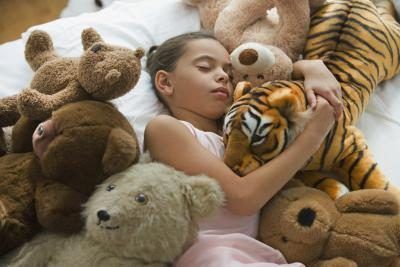 Jeune fille endormie avec des animaux en peluche