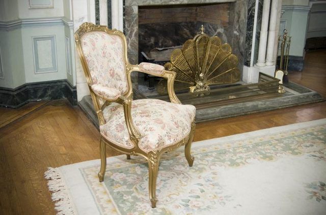 Une chaise peinte or devant accessoires en or sur le foyer.