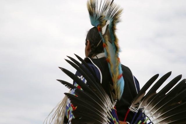 Un Amérindien vêtu de plumes vers le ciel.