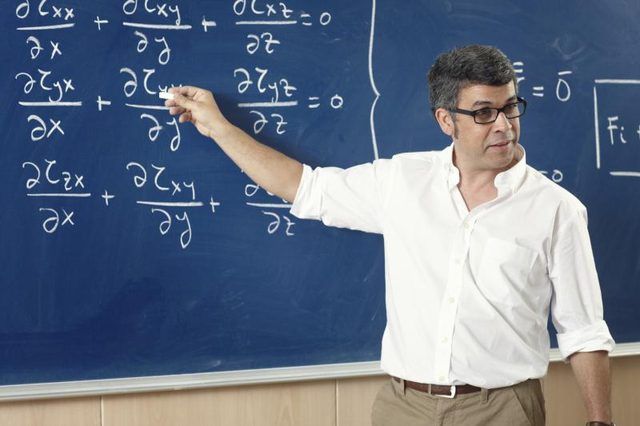 Un professeur de physique écrit des équations sur un tableau noir