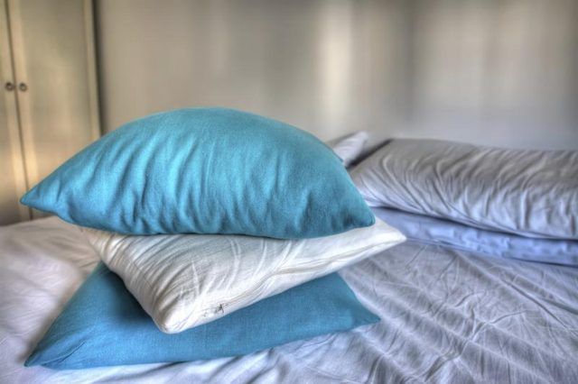 Une pile d'oreillers bleues et blanches sur le lit.