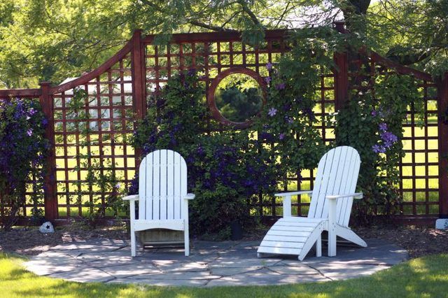 Une clôture en treillis derrière deux chaises longues.