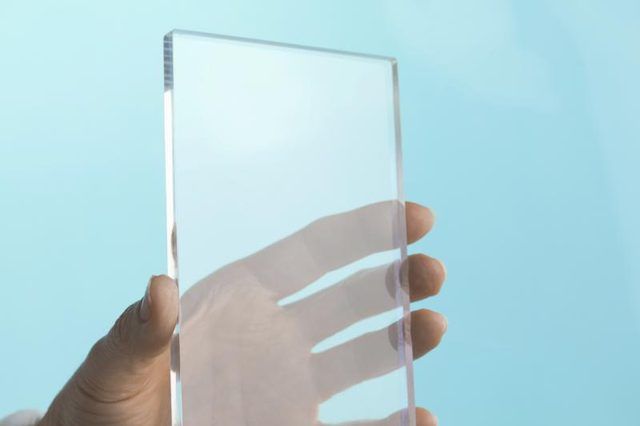 Une main tenant un morceau de plexiglas.